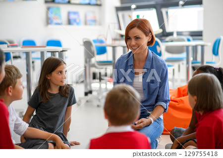 School kids and teacher sitting in circle on floor, talking about emotions. Morning Circle. 129755418