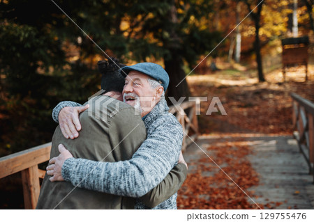 Grandad and grandson hugging in the middle of autumn park. Grandad and grandson hugging in the middle of autumn park. 129755476