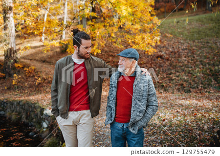 Senior father and his son walking in nature, talking. Senior father and his son walking in nature, talking. 129755479