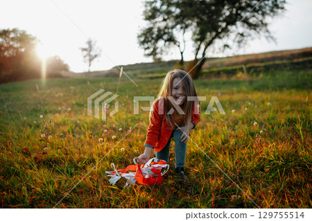 Girl playing with a rainbow hand kite in autumn nature at sunset. 129755514