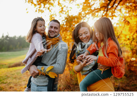 A portrait of young family with two small children in autumn nature at sunset. A portrait of young family with two small children in autumn nature at sunset. 129755525