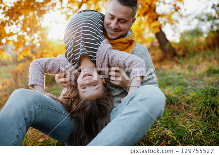 Father and young girl on walk in autumn nature, spending sunday outdoors. 129755527