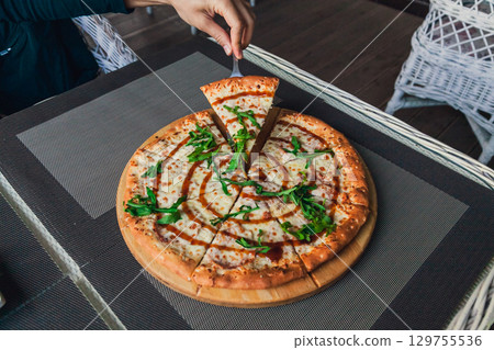 Man takes a slice of pizza from a whole on a gray background in a street cafe, top view Man takes a slice of pizza from a whole on a gray background in a street cafe, top view 129755536