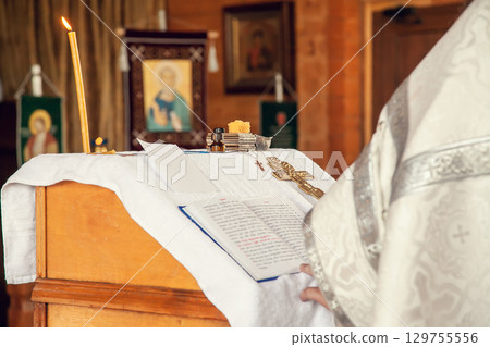A priest holds a book for reading prayers during the rite of baptism in the Orthodox Church 129755556