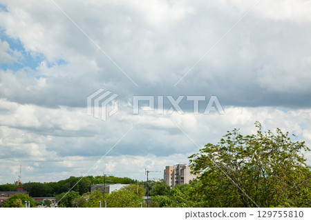 White clouds in the blue sky over the city and trees Clear blue sky with plain white cloud with space for text background White clouds in the blue sky over the city and trees Clear blue sky with plain white cloud with space for text background 129755810
