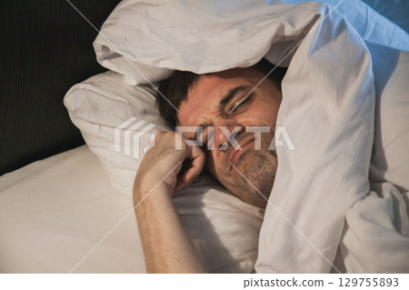 Struggling to wake up in bed after a long night of sleep during morning hours Struggling to wake up in bed after a long night of sleep during morning hours 129755893