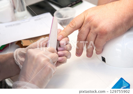 Men's manicure. A manicure master files the nails of a man in a beauty salon. Beauty industry Men's manicure. A manicure master files the nails of a man in a beauty salon. Beauty industry 129755902