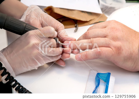 Mens manicure. A manicure master makes a hardware manicure for a man in the salon. Beauty industry Mens manicure. A manicure master makes a hardware manicure for a man in the salon. Beauty industry 129755906