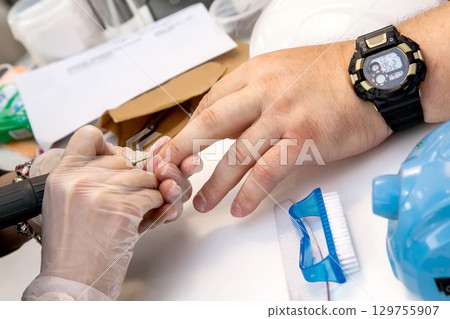 Mens manicure. A manicure master makes a hardware manicure for a man in the salon. Beauty industry Mens manicure. A manicure master makes a hardware manicure for a man in the salon. Beauty industry 129755907