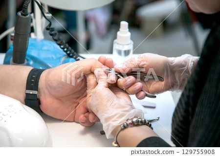 Men's manicure. A manicure master handles a man's nails with nail clippers in a beauty salon. Beauty industry Men's manicure. A manicure master handles a man's nails with nail clippers in a beauty salon. Beauty industry 129755908