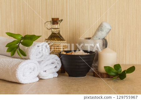 Spa, beauty and wellness background: towel, cosmetic massage oil, fresh leaf, sea salt with shells and candle 129755967