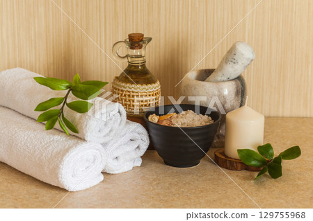 Spa, beauty and wellness background. Towel, cosmetic massage oil, leaf, sea salt with shells and candle Spa, beauty and wellness background. Towel, cosmetic massage oil, leaf, sea salt with shells and candle 129755968