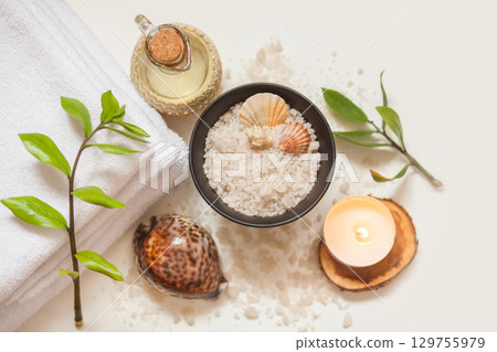 Spa, beauty and wellness background. Towel, cosmetic massage oil, leaf, sea salt with shells and candle Spa, beauty and wellness background. Towel, cosmetic massage oil, leaf, sea salt with shells and candle 129755979