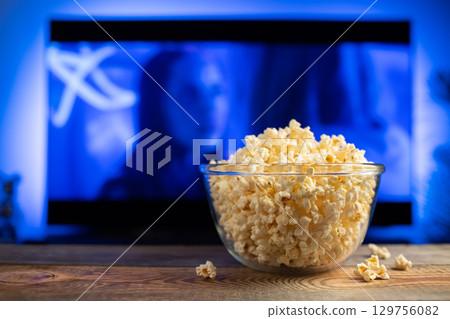 A glass bowl of popcorn and remote control in the background the TV works 129756082