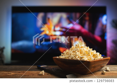 A wooden bowl of popcorn and remote control in the background the TV works 129756083