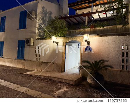 A stone wall with open entrance and glowing lanterns shows a cozy courtyard in the evening. Tradition, hospitality and cultural atmosphere symbolized by illuminated architecture. A stone wall with open entrance and glowing lanterns shows a cozy courtyard in the evening. Tradition, hospitality and cultural atmosphere symbolized by illuminated architecture. 129757263