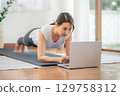 Asian woman doing plank exercise at home with laptop 129758312