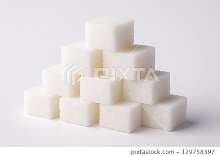 Pyramid of white sugar cubes arranged on a plain surface. concept of sweetness, culinary ingredient, kitchen staple 129758397