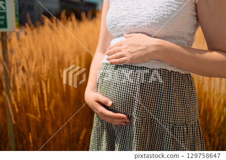 Pregnant Woman Holding Belly in Golden Wheat Field Pregnant Woman Holding Belly in Golden Wheat Field 129758647
