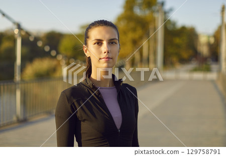 Close up portrait of sporty confident girl looking cheerful at camera standing outdoors. Close up portrait of sporty confident girl looking cheerful at camera standing outdoors. 129758791