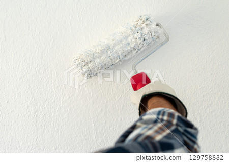 House painter worker painting a wall white. Building. 129758882