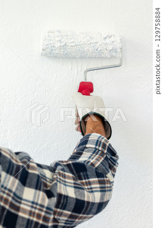 House painter worker painting a wall white. Building. 129758884