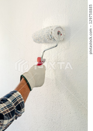 House painter worker painting a wall white. Building. 129758885