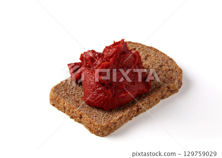 pile of tomato paste on a piece of rye bread isolated on white background. pile of tomato paste on a piece of rye bread isolated on white background. 129759029