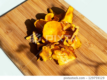 Vibrant yellow chanterelle mushrooms arranged on wooden cutting board, showcasing their unique shapes and textures, vegetarian culinary inspiration and gourmet cooking, Cantharellus cibarius, girolle Vibrant yellow chanterelle mushrooms arranged on wooden cutting board, showcasing their unique shapes and textures, vegetarian culinary inspiration and gourmet cooking, Cantharellus cibarius, girolle 129759129