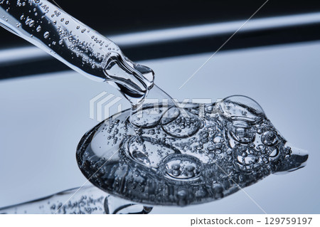The texture of the serum with bubbles spilling onto the blue surface. 129759197