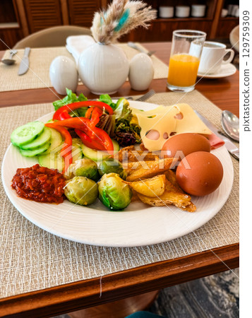 A breakfast plate with eggs, cheese, vegetables and potatoes on a restaurant table. Nutrition, balance, energy and morning wellness in a hotel dining atmosphere. 129759309