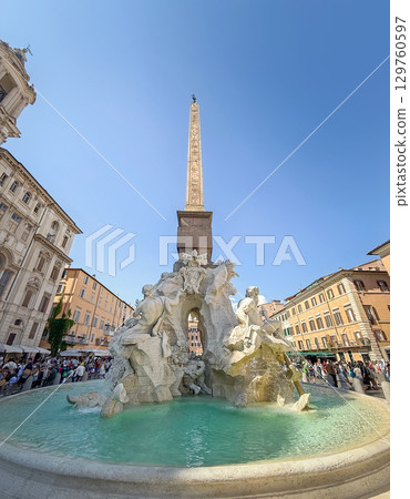 An iconic Baroque masterpiece by Bernini, the Fountain of the Four Rivers dominates Piazza Navona in Rome, Italy. It features a central obelisk and allegorical statues of four river gods 129760597