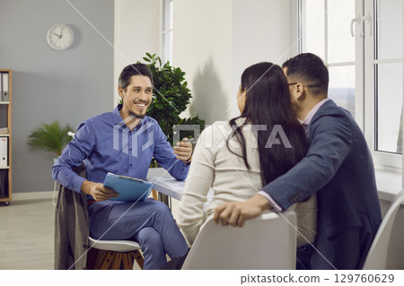 Young couple sitting back and having consultation with a man realtor or insurance agent at office. Young couple sitting back and having consultation with a man realtor or insurance agent at office. 129760629