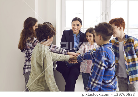 Group of happy school children together with teacher learning what support and teamwork are 129760658