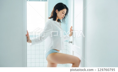 一名女子身穿濕襯衫站在浴室入口處 129760795