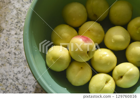 A ripe yellow plum in a green basin. Juicy fruit. Ripe plums in drops of water. A ripe yellow plum in a green basin. Juicy fruit. Ripe plums in drops of water. 129760816