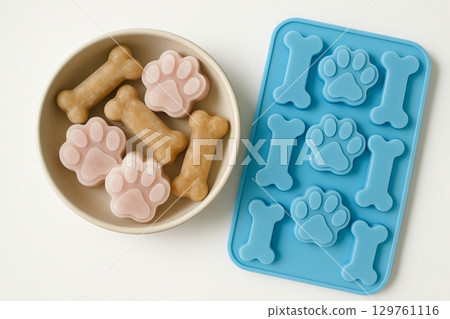 Frozen treats for dogs in bone and paw shapes to keep pets cool and happy during summer. concept of pet care, dog snacks, summer treats 129761116