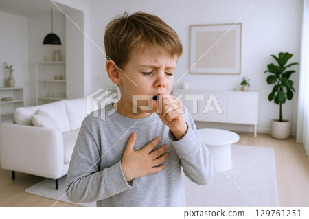 Young child coughing at home in a cozy living room environment. concept of child health, home comfort, illness care, everyday childhood experience. 129761251