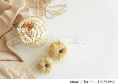 Cozy pumpkin latte with whipped cream and spices, surrounded by autumn decor. Cozy pumpkin latte with whipped cream and spices, surrounded by autumn decor. 129761698