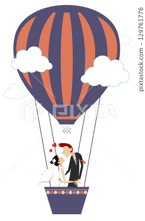 Married wedding couple flying up on the air balloon. Heart symbol and kissing married wedding couple fly up on the air balloon. Wedding ceremony. 129761776