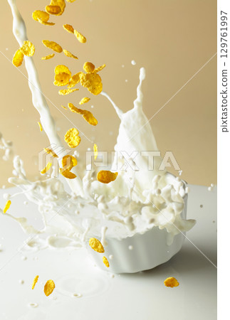 Dry honey cornflakes with milk splashes in a ceramic plate. 129761997