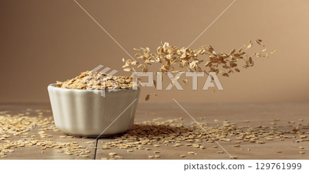 Oat flakes in motion on a beige background. Oat flakes in motion on a beige background. 129761999