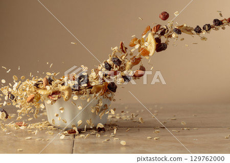 Muesli in motion on a beige background. Muesli in motion on a beige background. 129762000