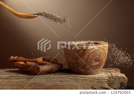 Chia seeds is poured into a wooden bowl. 129762001