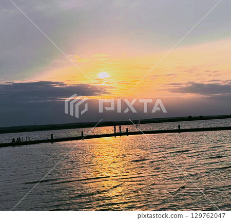 Golden sunset with few clouds over a beautiful and calm lake in Europe 129762047