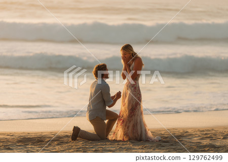 Couple proposing at the beach at sunset | A touching romantic moment 129762499