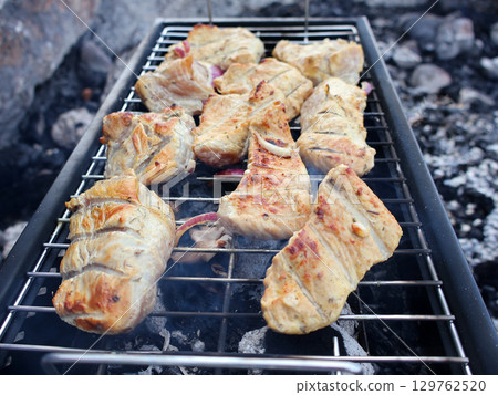 Grilled Meat Cooking Outdoors on a Barbecue open Fire in a Rustic Setting 129762520