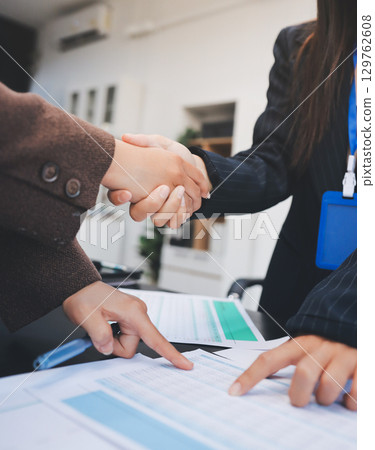 Business people shaking hands in office. Two business partners shaking hands after signing a contract in office. Business people shaking hands in office. Two business partners shaking hands after signing a contract in office. 129762608