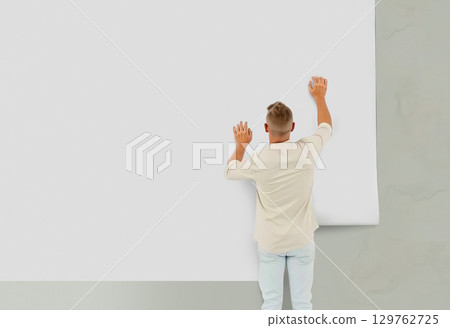 Man applying blank white wallpaper roll to wall, ai generated 129762725