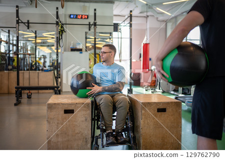 Wheelchair athlete trains with medical ball. Spinal injury rehabilitation under coach supervision 129762790